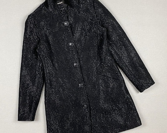May include: Black long coat with a floral pattern and a stand-up collar. The coat has a button-up front and long sleeves. The brand name "Desigual" is visible on the collar.