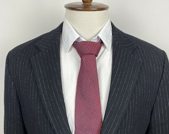 May include: A black pinstripe suit jacket with a red and blue patterned tie.