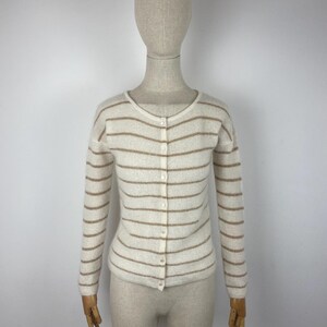 May include: A white and brown striped cardigan with a button closure. The cardigan is made of a soft, knit fabric.