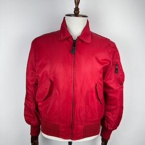 May include: A red bomber jacket with a zip fastening and two pockets on the front. The jacket has a ribbed collar and cuffs.