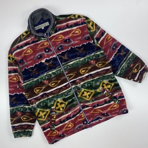 Puede incluir: Una chaqueta de forro polar multicolor con cierre de cremallera y estampado paisley. La chaqueta tiene cuello alto y mangas largas.