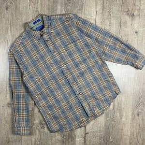 Peut inclure: Une chemise à carreaux à manches longues en bleu, marron et blanc. La chemise a un col boutonné et une fermeture boutonnée.