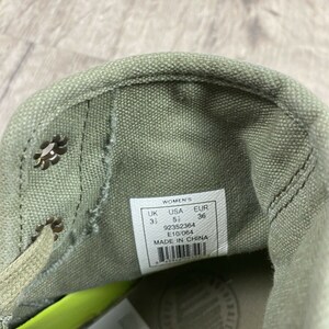 K&ouml;nnte beinhalten: Nahaufnahme des Innenraums eines gr&uuml;nen Canvas-Schuhs mit einem wei&szlig;en Etikett mit der Aufschrift "Women's UK 3 1/2 USA 5 1/2 EUR 36 92352364 E10/064 MADE IN CHINA".