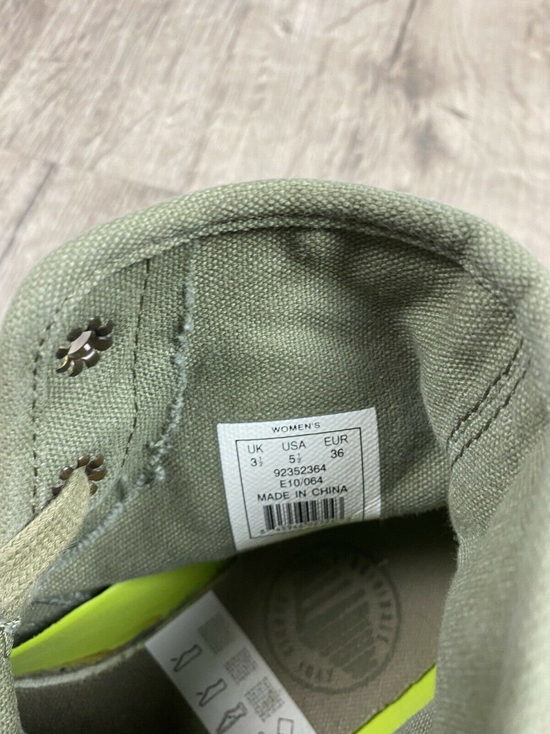 K&ouml;nnte beinhalten: Nahaufnahme des Innenraums eines gr&uuml;nen Canvas-Schuhs mit einem wei&szlig;en Etikett mit der Aufschrift "Women's UK 3 1/2 USA 5 1/2 EUR 36 92352364 E10/064 MADE IN CHINA".