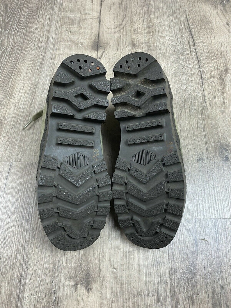 K&ouml;nnte beinhalten: Ein Paar schwarze Gummisohlige Stiefel mit einem Profilmuster. Die Stiefel sind aus hellgr&uuml;nem Canvas-Material gefertigt.