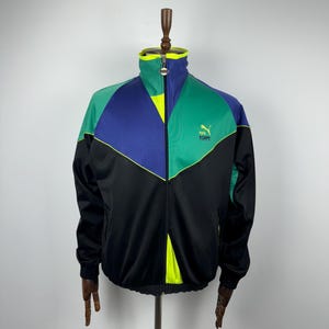 May include: A vintage Puma track jacket in black, green, blue and yellow with a zip fastening. The jacket features a Puma logo on the chest.