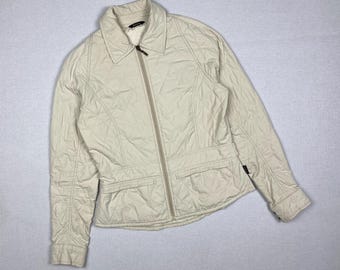 May include: A cream-colored quilted jacket with a zipper closure and a small black label on the sleeve.