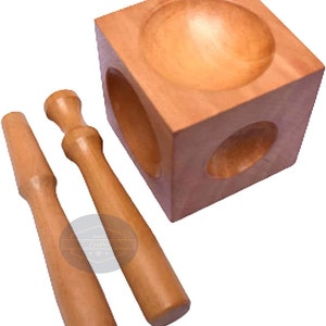 May include: A wooden jewellery making set. It includes a cube with a rounded indentation and two wooden tools. The cube has a hole on two sides. The tools are cylindrical with rounded ends. The set is made of light brown wood.