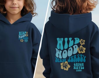 May include: Navy blue hoodie with a front pocket and a hood. The front of the hoodie has the text "Wildwood New Jersey" with a flower graphic. The back of the hoodie has the same text and flower graphic, with the words "Catch Waves 1895".