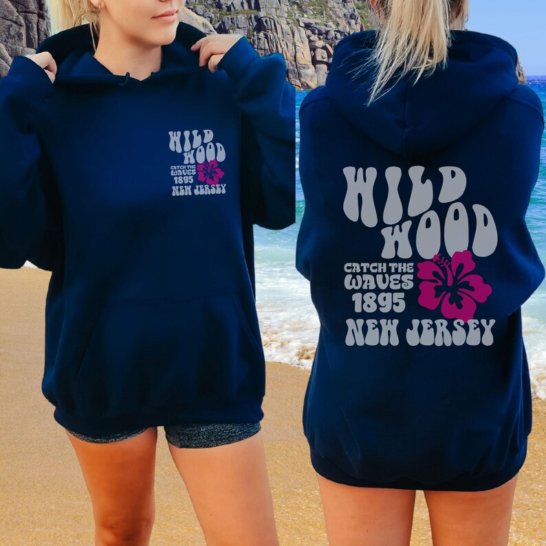 Może przedstawiać: Granatowa bluza z kapturem z napisem "WILD WOOD CATCH THE WAVES 1895 NEW JERSEY" w białym i szarym kolorze. Na plecach bluzy nadrukowany jest r&oacute;żowy kwiat hibiskusa.