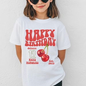 May include: White t-shirt with a red "Happy Birthday" design. The shirt features the name "Julianna", the number "12", and a pair of cherries. The text "Make Memories" and "Est. 2013" are also included.