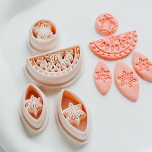 May include: A collection of light peach-colored polymer clay cutters in various shapes, including a circle, oval, and a watermelon slice. Each cutter features a detailed snowflake design, perfect for crafting and DIY projects.