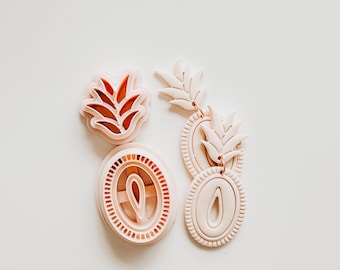 May include: Four light pink polymer clay cutters for crafting. The cutters include two leaf-shaped designs, and two oval-shaped designs with interior cutouts. The cutters are arranged on a white surface.