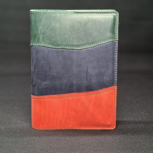 Puede incluir: Un diario encuadernado en cuero con un esquema de colores verde, azul y rojo. La cubierta está dividida en tres secciones, cada una de un color diferente.