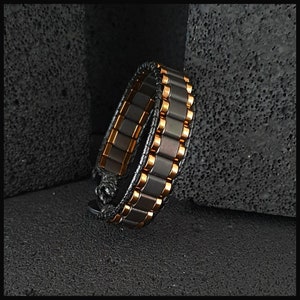 May include: A black and copper bracelet with a leather strap. The bracelet is made of small, rectangular tiles.