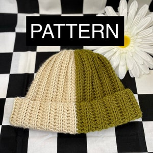 May include: A crocheted beanie hat with a cream and olive green color scheme. The hat is made with a ribbed stitch and has a folded brim.