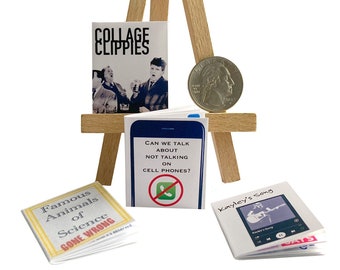 May include: Four miniature books on a wooden easel. The books are titled "Famous Animals of Science Gone Wrong", "Collage Clippies", "Can We Talk About Not Talking On Cell Phones?", and "Kayley's Song".