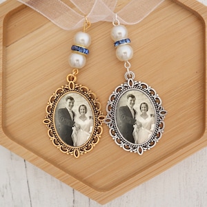 Peut inclure: Deux faveurs de mariage avec une photo d'un couple dans un cadre doré et argenté. Chaque faveur est ornée d'une perle blanche et d'un strass bleu.