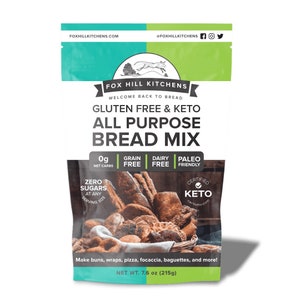 May include: A green, blue, and white bag of gluten-free and keto all-purpose bread mix. The bag features a fox logo and the text "Fox Hill Kitchens". The bag also includes a list of ingredients and nutritional information, including "0g net carbs", "grain free", "dairy free", and "paleo friendly". The bag also includes a photo of various breads made with the mix.