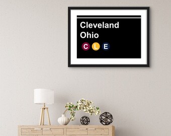 May include: Black and white subway sign with the text "Cleveland Ohio" and the letters "CLE" in red, yellow, and blue circles.