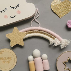 Peut inclure: Ensemble de décorations de chambre d'enfant faites à la main. Comprend un nuage blanc avec des yeux fermés, un arc-en-ciel avec des couches roses, dorées et blanches, une étoile dorée à paillettes et des poupées en bois.