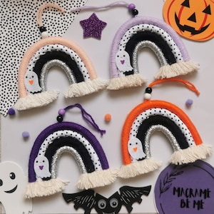 May include: Four handmade macrame rainbow ornaments with black and white polka dot fabric, silver glitter, and a ghost applique. The rainbows are in shades of orange, purple, pink, and lavender.