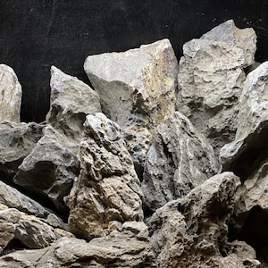 May include: A pile of gray and brown rocks with rough, uneven surfaces. The rocks are arranged in a random pattern, creating a natural and organic look.