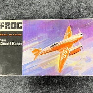 May include: A vintage FROG DH88 Comet Racer model kit box. The box art depicts an orange aeroplane in flight against a purple and yellow sky. The box has the text "FROG" and "The Trail Blazers".