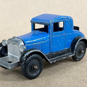 May include: A blue toy car with a black chassis and silver grill. The car has a black roof and black wheels.