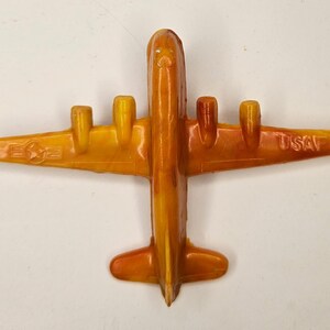 May include: A yellow plastic toy aeroplane with the text "USAF" on the wing. The aeroplane has four engines and a star on the side.
