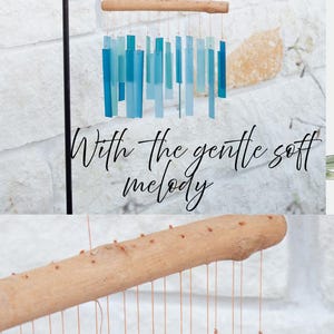 May include: A wind chime featuring rectangular glass pieces in various shades of blue and teal, suspended by thin strings from a natural driftwood branch. The text Relax With the gentle soft melody is displayed in black script over the chime.