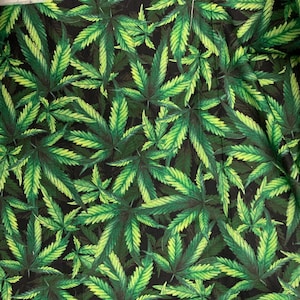 May include: Fabric with a repeating pattern of green and yellow cannabis leaves on a dark background. The leaves have detailed veining and a naturalistic appearance, creating a vibrant and eye-catching design.