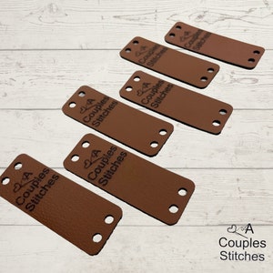 May include: Six brown leather labels with the text "2A Couples Stitches" in black lettering. The labels have four holes each.