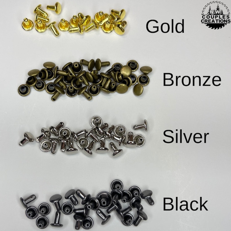 May include: Four piles of metal rivets in different colors: gold, bronze, silver, and black. The rivets are small and have a round head with a pointed shaft.