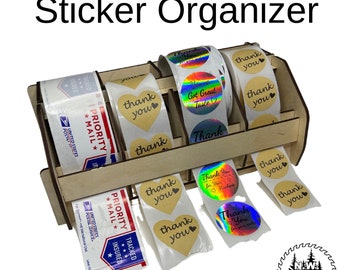 May include: A wooden sticker organizer with multiple compartments holding rolls of stickers and USPS Priority Mail labels. The stickers include heart-shaped and round designs with "thank you" and holographic text.