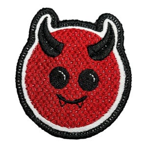 May include: Embroidered patch of a red devil face with black horns, eyes, and fangs. The patch has a white border and a black stitched edge. The design is in a cartoon style.