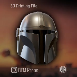 May include: A silver and black Mandalorian helmet, a 3D printing file. The helmet has a rounded top and angular faceplate. The text "3D Printing File" is at the top. The Instagram handle "BTM.Props" is at the bottom.