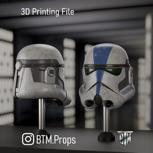 Puede incluir: Un archivo de impresión 3D para un casco de soldado clon con acabado blanco desgastado, una franja vertical azul en el centro, una visera verde oscuro y rejillas laterales. El texto 3D Printing File y BTM.Props es visible en la imagen.