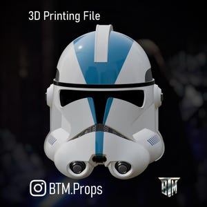 May include: A white and blue Clone Trooper helmet with black visor and details. The helmet features blue stripes and accents. The text "3D Printing File" is at the top. The Instagram handle "BTM.Props" is at the bottom.