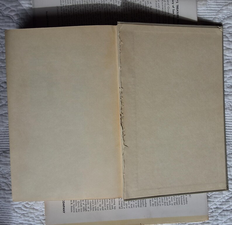 May include: An open book with aged, off-white pages. The binding is visible, showing the rough edges of the pages. Additional pages with text are partially visible, suggesting a vintage or antique book.