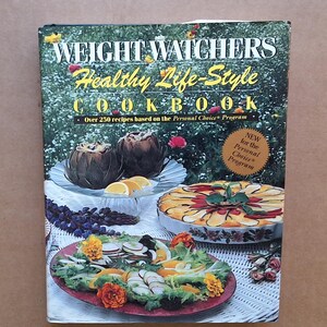 May include: A cookbook titled "Weight Watchers Healthy Life-Style Cookbook" with images of prepared dishes. The cover features text and images of food, including artichokes, sliced oranges, and a colorful vegetable dish. The book promotes recipes based on the Personal Choice Program.