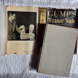 May include: An open book and several pamphlets are displayed with a hardcover book titled "Gump's Treasure Trade." The book's cover is black with gold lettering. The pages show text and a black and white photo.