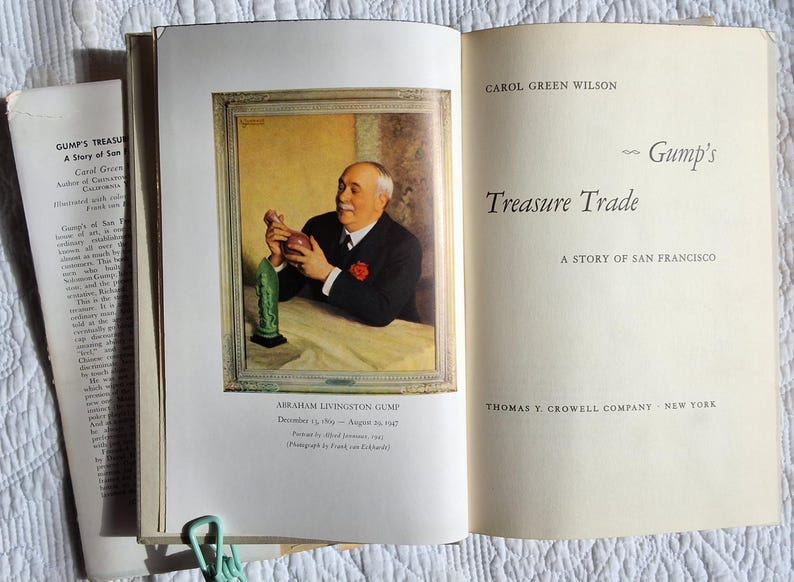 May include: Open book with a portrait of Abraham Livingston Gump holding a decorative object. The book's title is "Gump's Treasure Trade: A Story of San Francisco" by Carol Green Wilson. The book is open to a page with text.