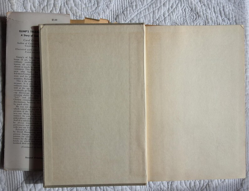 May include: An open vintage book with aged, cream-colored pages. The left side shows the text of the book, while the right side is blank. The book's cover is visible, with the title "Gump's Treasure" and author information.