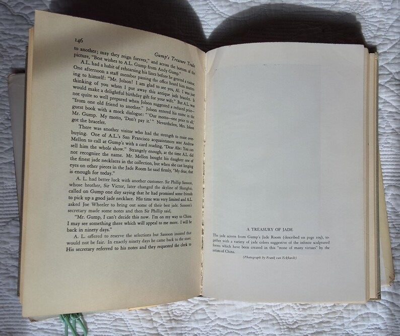 May include: Open book with text on the left page and a blank page with text at the bottom on the right. The text on the right page reads "A Treasury of Jade". The book is open on a white surface.