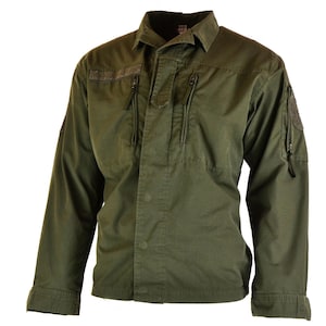 Op de afbeelding: Olijfgroene jas in militaire stijl met een knoopsluiting en een kraag. Voorzien van meerdere zakken met ritssluiting op de borst en mouwen, en patches op de bovenarmen. De jas met lange mouwen heeft een klassiek, functioneel ontwerp.