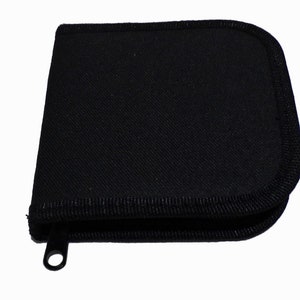 May include: A black zippered case with a fabric exterior and a black zipper pull.