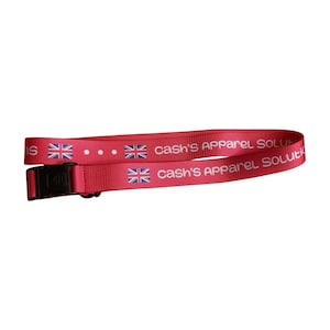 Puede incluir: Lanyard rojo con una hebilla de plástico negro. El lanyard tiene el texto "Cash's Apparel Solutions" y una imagen repetida de la bandera del Reino Unido.