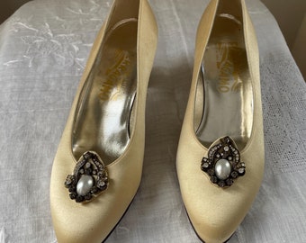 May include: A pair of ivory satin pumps with a low heel and a jeweled embellishment on the toe. The shoes are made by Salvatore Ferragamo.