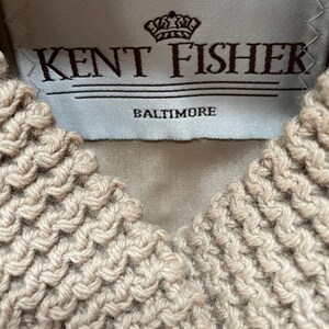 May include: A white label with brown text that reads "Kent Fisher Baltimore" and a crown logo above the text.